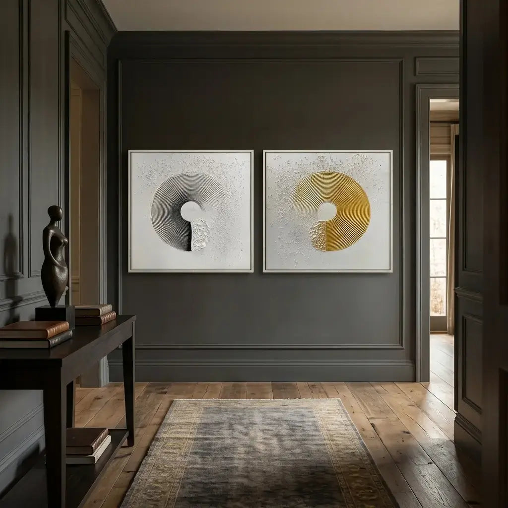 Two abstract art pieces on a dark wall in a room with wooden flooring.
