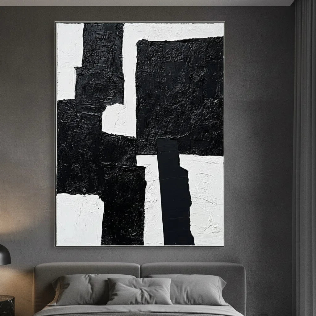 Abstract black and white painting on a gray wall above a bed.