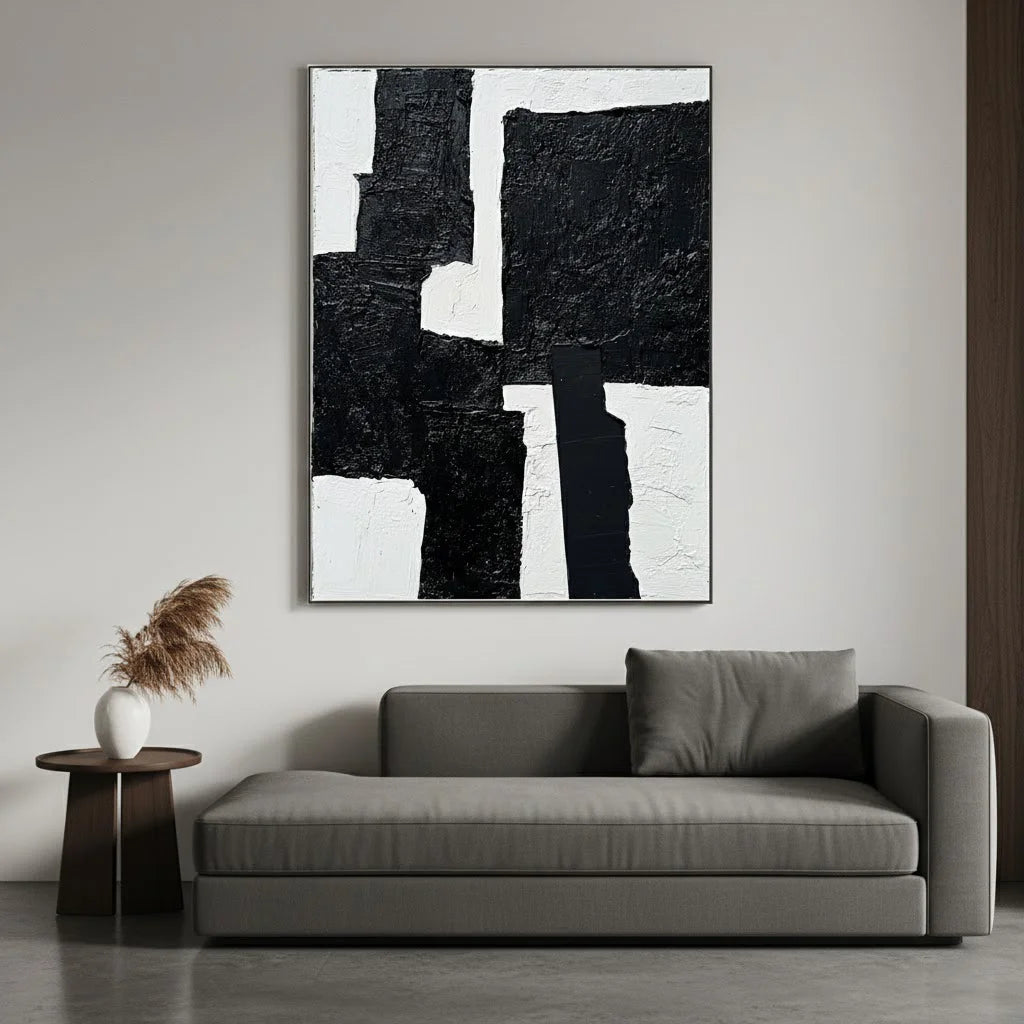 Abstract black and white painting above a gray sofa in a modern living room.
