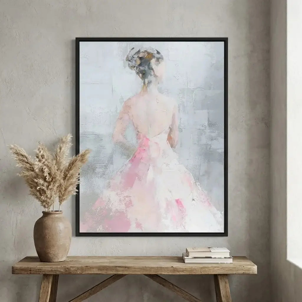Framed abstract art of a woman in a pink dress on a wall above a wooden table.